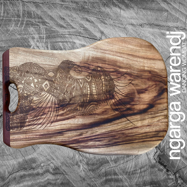 Bunjil Eagle in Cloak Board Made from Camphor Laurel with One Redgum Handle. Each board has its own distinct natural pattern and is embellished with a Bunjil Design by Ngarga Warendj - Dancing Wombat - based on the Traditional symbols of South Eastern Aboriginal Art. Your board comes with a card that gives the story of the artist and design.