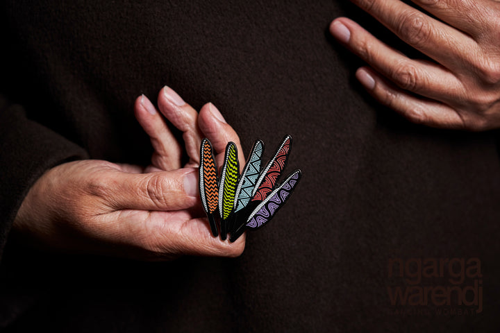 In its stylish box with magnetic closure, this pin is perfect for gift giving. This Lapel Pin featuring our Five Feathers design by Ngarga Warendj (Dancing Wombat), will add a finishing touch to any outfit. This design is inspired by Bunjil, Our creator ,with each of the feathers representing one of the five language groups of the Eastern Kulin Nations. Measures 55 mm x 53.7mm