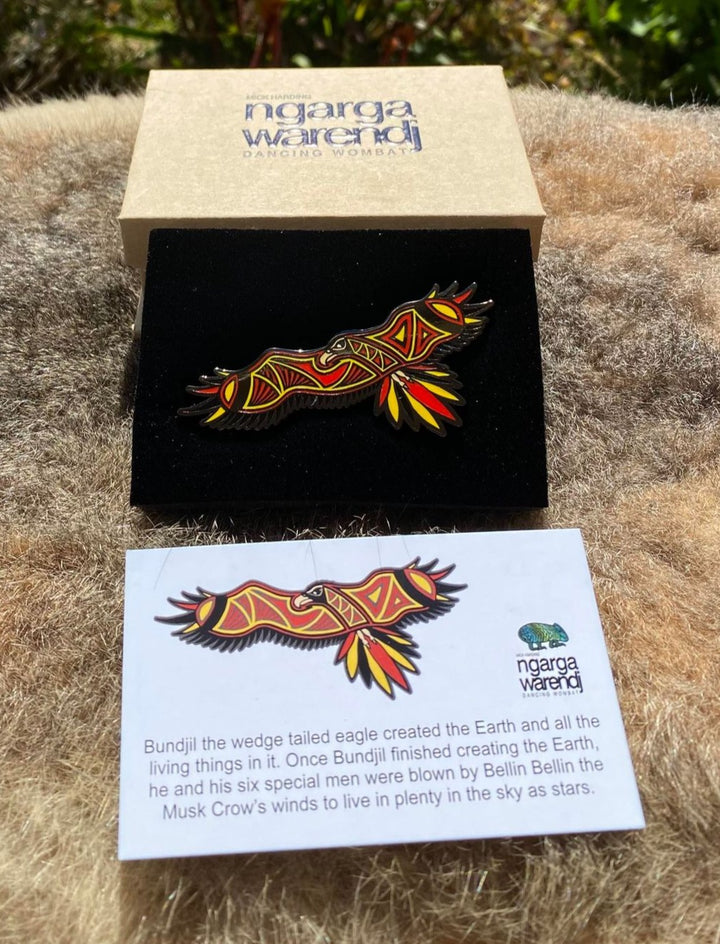 Add a finishing touch to any outfit, with this Lapel Pin featuring a Bunjil the Wedge Tailed Eagle design by Ngarga Warendj Dancing Wombat.  Our new design features bold red, yellow and black colors. Measures 65mm x 35.5mm  Presented in a stylish box with magnetic closure  Made with metal with enamel inlay Includes an information card on the design and artist
