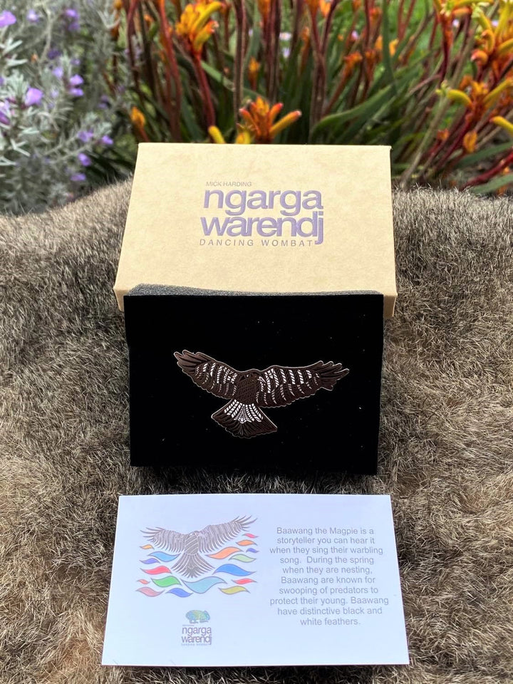 Add a finishing touch to any outfit, with this Lapel Pin featuring a Baawang the Magpie design by Ngarga Warendj Dancing Wombat. Measures 60mm x 32.4mm  Presented in a stylish box with magnetic closure  Made from metal with enamel inlay Information card included - with information on the design and artist