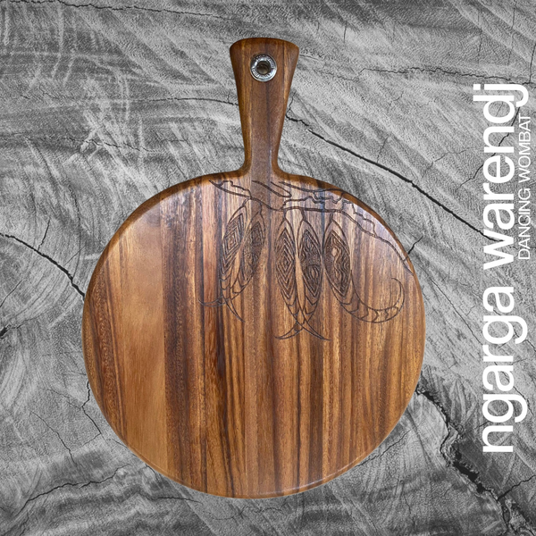 Acacia Wood Medium Round Paddle Board - Gum Leaves branch Design Each board has its own distinct pattern and is embelished with a Design by Ngarga Warendj - Dancing Wombat - based on the Traditional symbols of South Eastern Aboriginal Art. Your board comes with a card that gives the story of the artist and design. Our boards are perfect for a house warming gift or spoil yourself and bring art into your everyday