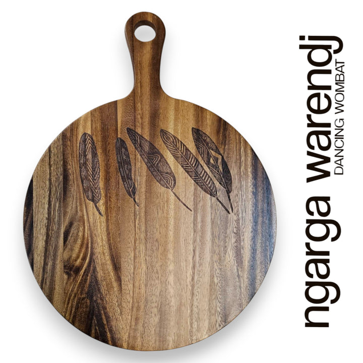 Wooden cutting board with feather design on a white background, featuring the brand 'ngarga warendj'.