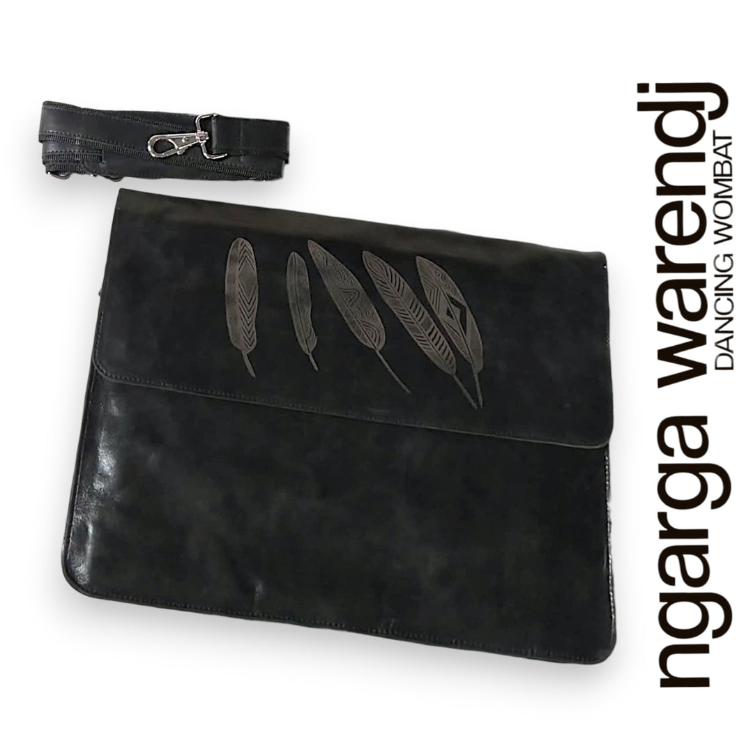 Black clutch bag with feather design and matching strap on a white background, featuring the brand 'ngarga warendj'.