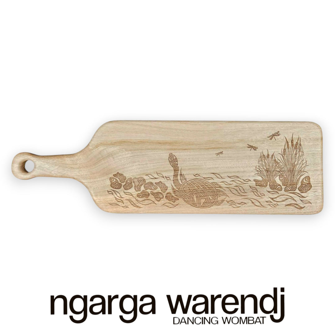 Wooden cutting board with engraved design of a wombat and plants on a white background, featuring the brand 'ngarga warendj'.