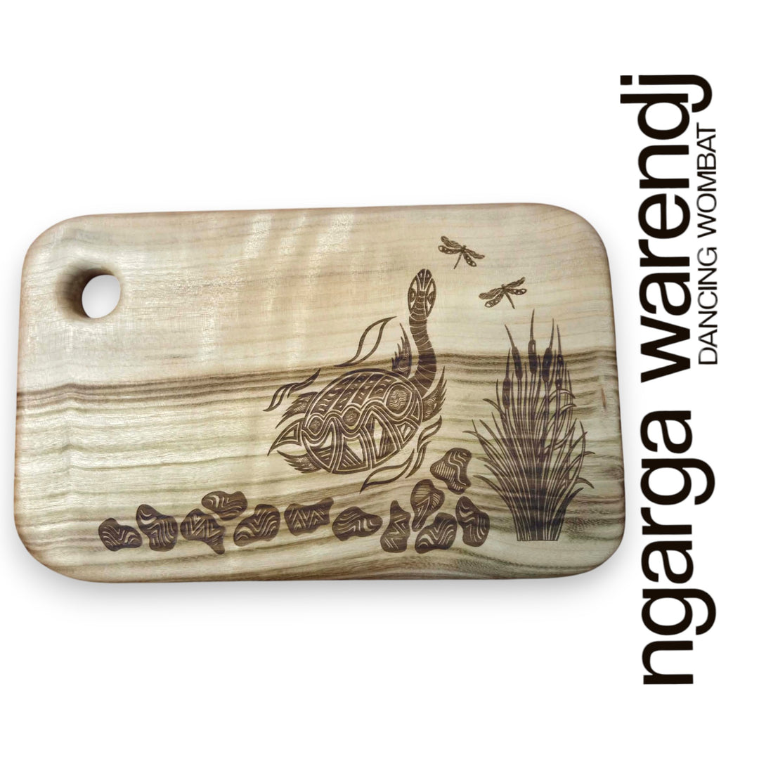 Wooden cutting board with laser-engraved designs on a white background, featuring the brand 'ngarga warendj'.