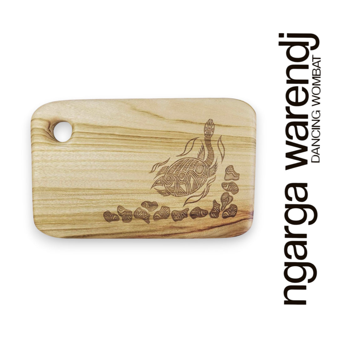 Wooden cutting board with turtle design and 'ngarga warendj' branding on a white background
