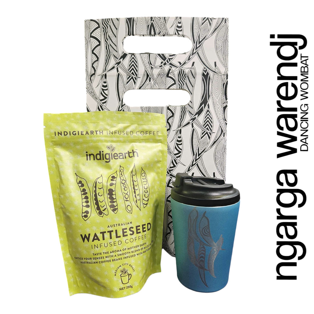 Indigiearth wattleseed infused coffee package with a blue reusable cup and patterned bag on a white background.