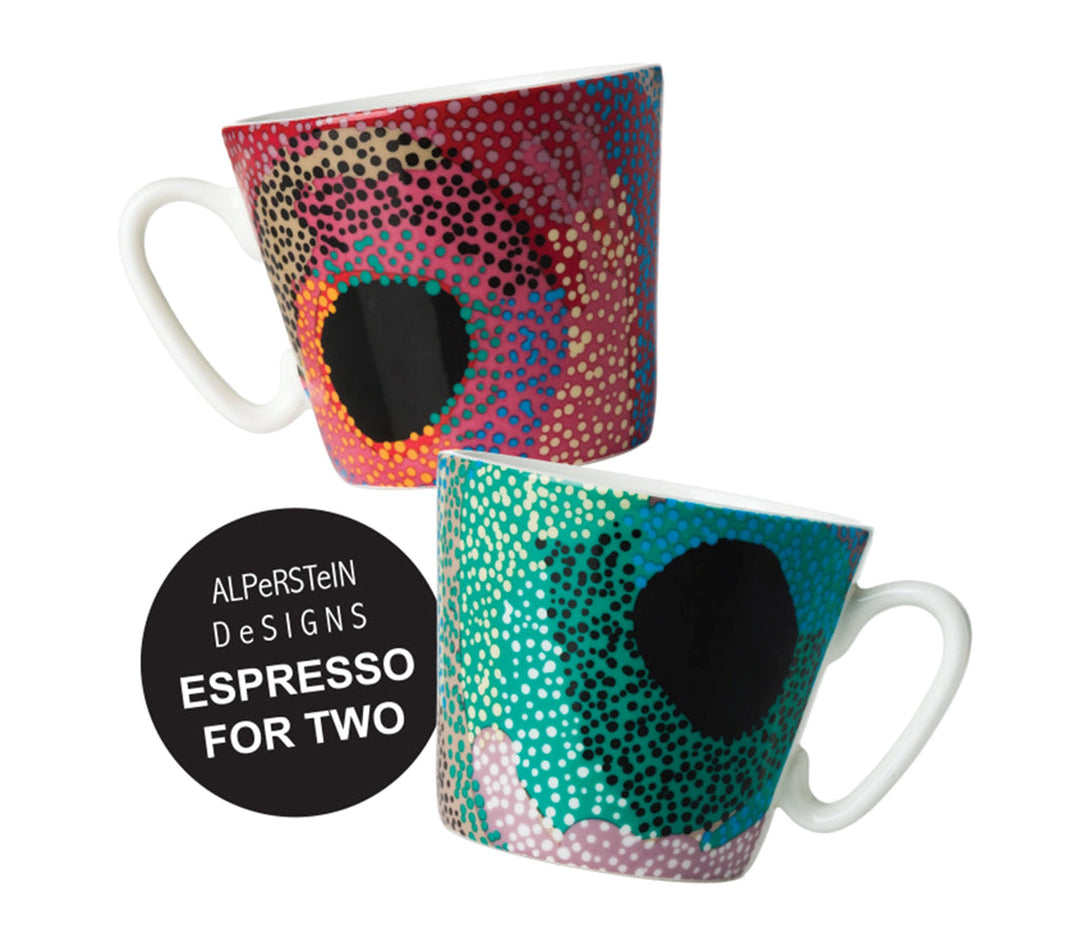 Two ceramic mugs with a modern dot-art style eye design, shown on a white background with a black circular badge that reads 'ALPerSTeln DeSIGNS ESPRESSO FOR TWO'. The top mug has a red, black, and gold pattern, and the bottom mug has a teal, black, and pink pattern.