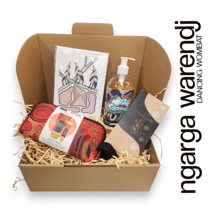 Gift box with various items including a pouch with hand cream and lip balm , hand and body wash, chocolate and card, branded 'ngarga warendj'.