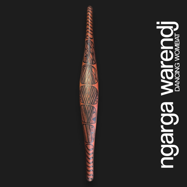 Front of large red cedar parrying shield with Gugra Possum Cloak Design, featuring dark geometric panels and curved lines.