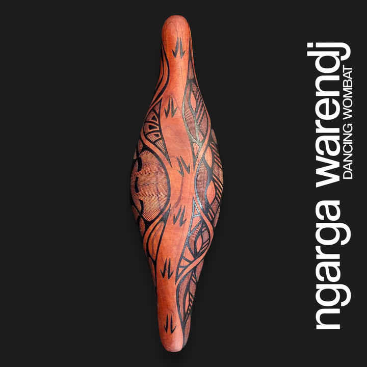 Front of small wide Australian Red Cedar parrying shield with black Barring track marks and geometric linework on timber.