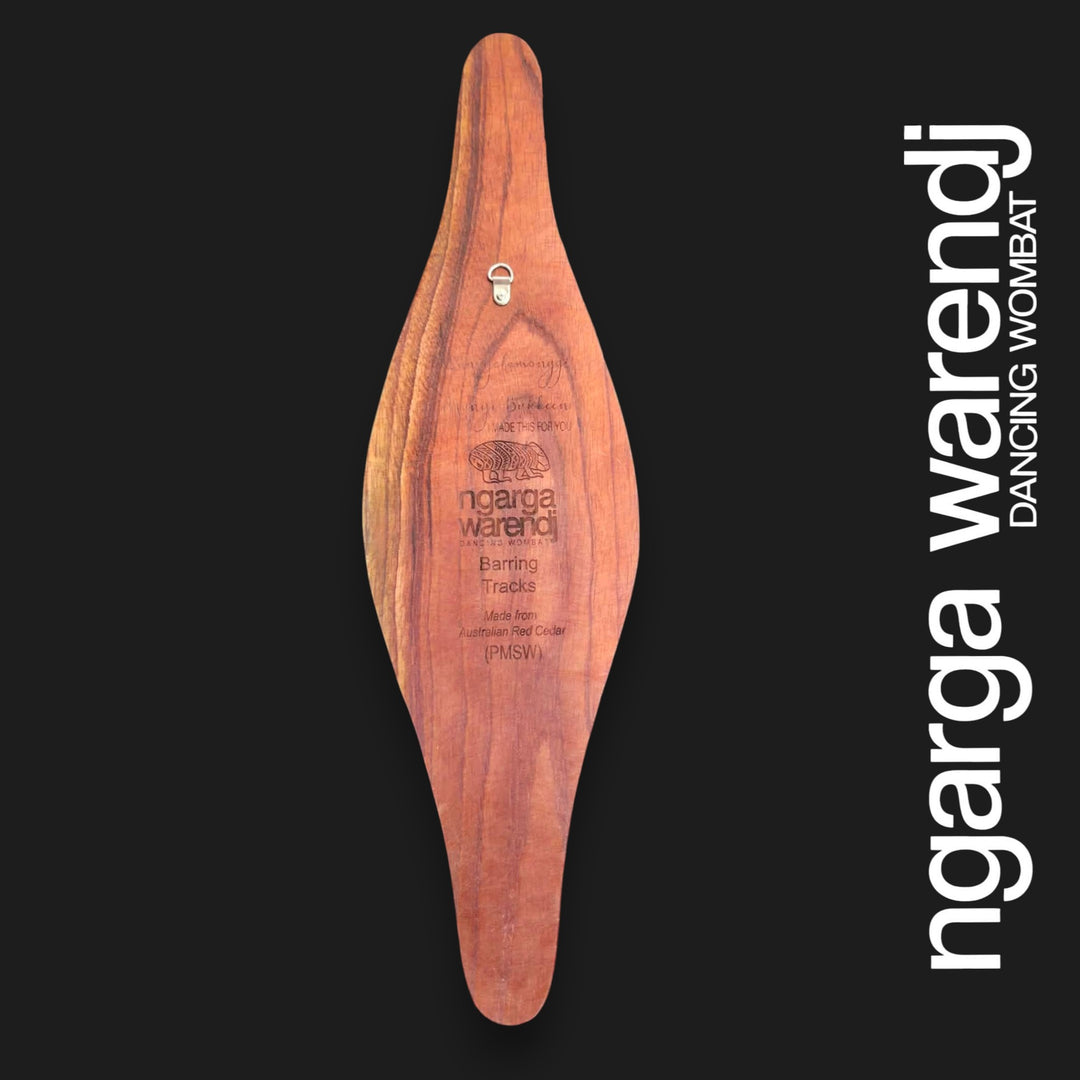 Back of small wide Australian Red Cedar parrying shield showing natural timber grain, engraved information and an attached wall hanger.