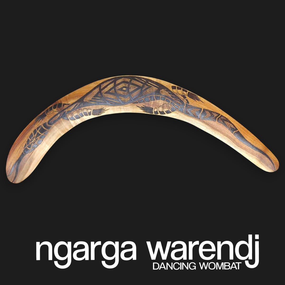 Decorative boomerang with artistic design on a black background, featuring the brand 'ngarga warendj'.