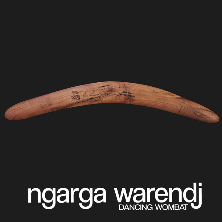Wooden boomerang with 'ngarga warendj' branding on a black background