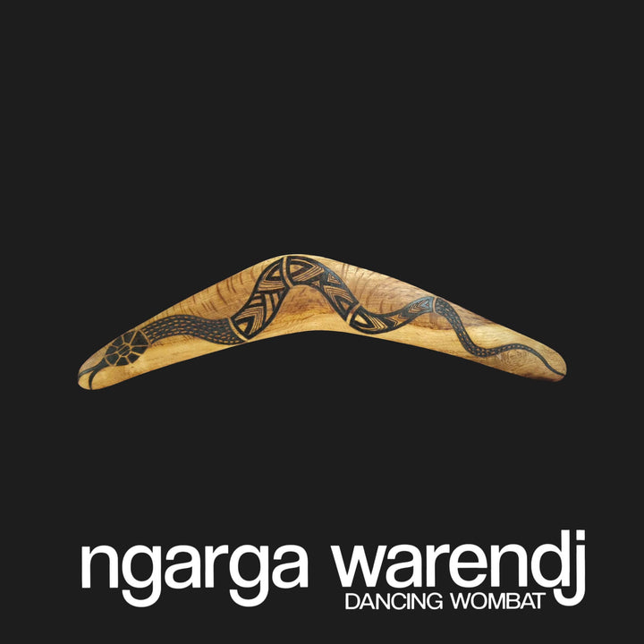 Wooden boomerang with tribal patterns on a black background, featuring the brand 'ngarga warendj'.
