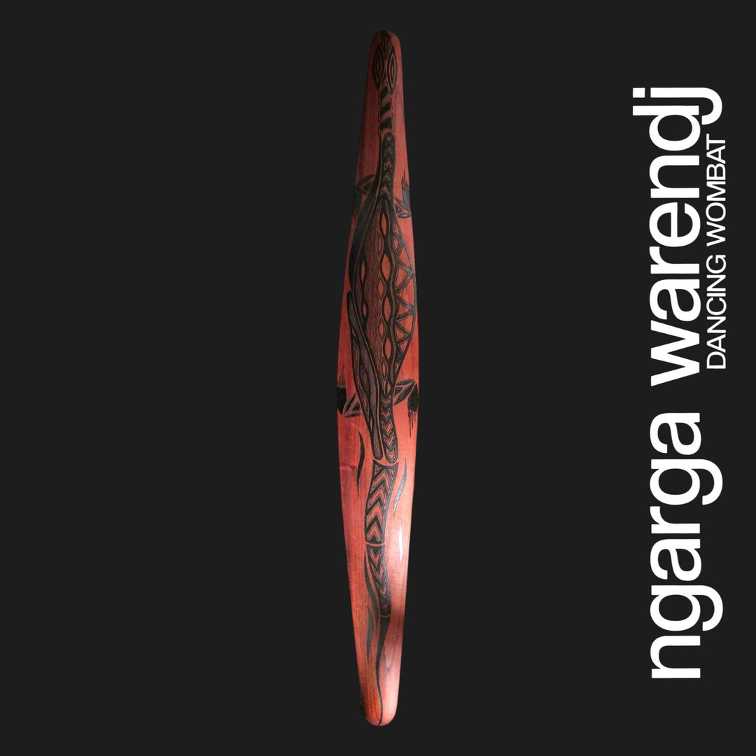 Front of large red cedar wall shield featuring Dhulin the goanna in black patterned linework with a long tail.