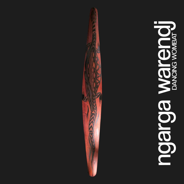 Front of large red cedar wall shield featuring Dhulin the goanna in black patterned linework with a long tail.
