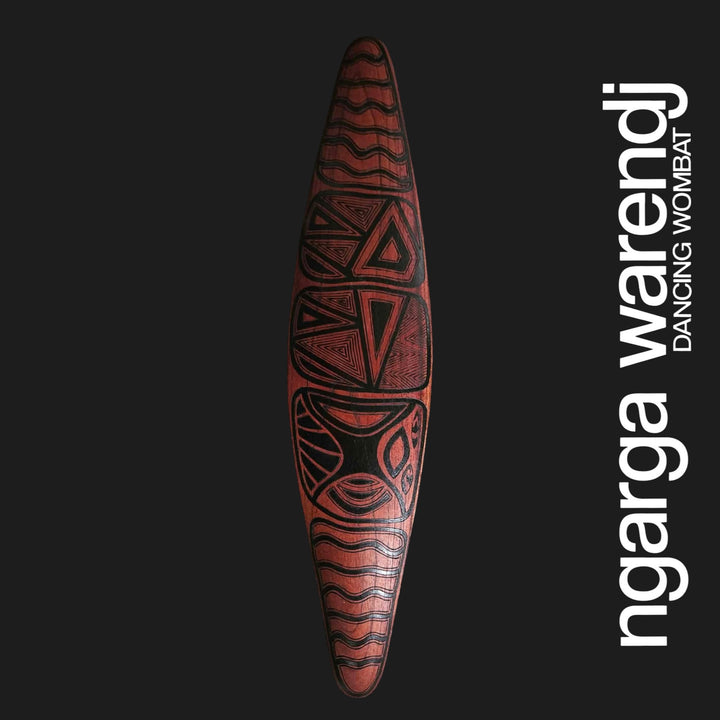 Front of small red cedar wall shield with Gugra Possum Cloak design, carved triangles and curved black linework.