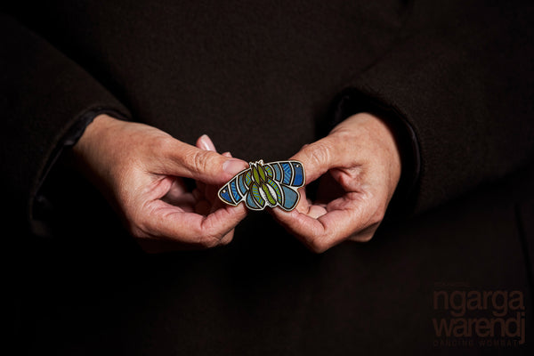 Add a finishing touch to any outfit, with this Lapel Pin featuring a Blue Bogong Moth design by Ngarga Warendj Dancing Wombat Measures 50mm x 36.8mm  Presented in a stylish box with magnetic closure  Information card included - with information on the design and artist  Metal with Enamel Inlay