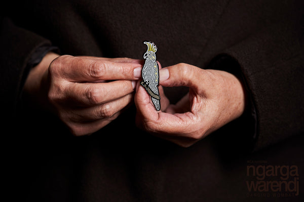 This lapel pin featuring our cockatoo design, by Ngarga Warendj Dancing Wombat, will add a finishing touch to any outfit,  Measures 60mm x 30.7mm  Presented in a stylish box with magnetic closure  Made from metal with enamel inlay Information card included - with information on the design and artist 
