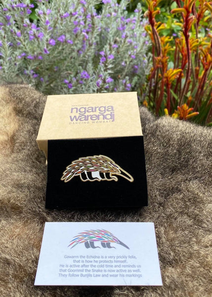 Add a finishing touch to any outfit, with this Lapel Pin featuring our Echidna design by Ngarga Warendj Dancing Wombat Measures 65mm x 25mm  Presented in a stylish box with magnetic closure  Made from metal with an enamel inlay Information card included - with information on the design and artist 