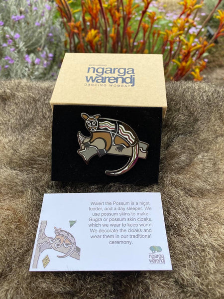 Add a finishing touch to any outfit, with this Lapel Pin featuring Walert the Possum design by Ngarga Warendj Dancing Wombat. Measures 60mm x 44.7mm  Presented in a stylish box with magnetic closure  Made from metal with enamel inlay Information card included - with information on the design and artist 